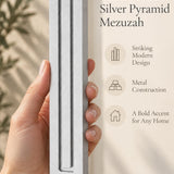 Hand holding the Giant Modern Silver Pyramid Mezuzah upright, revealing its softly brushed silver aluminum mezuzah cover, slender three-bar Pyramid design and graduated top beside illustrated product features for architectural Jewish home Judaica