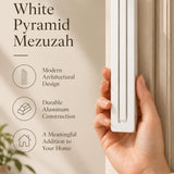 A hand presents the Giant Modern White Pyramid Mezuzah with its smooth matte white aluminum mezuzah cover facing forward, highlighting the clean graduated bars and geometric vertical profile beside design illustrations for a architectural Jewish doorway accent