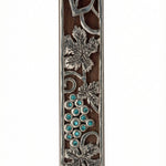 Mahogany mezuzah with curling pewter vine and turquoise stones, depicting one of the seven species of the holy land, detailed and crafted with fine finishing.