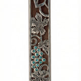Mahogany mezuzah with curling pewter vine and turquoise stones, depicting one of the seven species of the holy land, detailed and crafted with fine finishing.