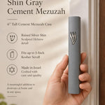 Handheld gray cement mezuzah case with a raised sculptural silver-tone Shin, shown beside product details to illustrate the slim proportions, smooth cement finish, minimalist design, and modern Jewish doorway style