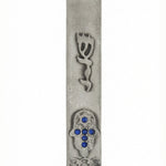 Bright blue accent stones adorn a Hamsa shape pewter Mezuzah, set on a clean white background with subtle reflection, highlighting intricate design details.