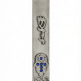 Bright blue accent stones adorn a Hamsa shape pewter Mezuzah, set on a clean white background with subtle reflection, highlighting intricate design details.