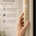 Hand holding the Etz Chaim cream Jerusalem stone mezuzah, showing scale and stone color.