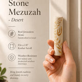 Person holding authentic Jerusalem stone mezuzah with gold olive branch in a natural pose for premium product presentation