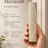Person holding a Jerusalem stone Mezuzah in natural light, highlighting its texture and craftsmanship in a premium store setting.