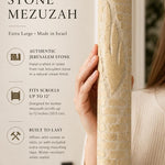 Person holding the Jerusalem Stone Mezuzah showing its carved Hebrew letter and textured surface in a premium editorial style.