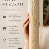 Person holding the Jerusalem Stone Mezuzah showing its carved Hebrew letter and textured surface in a premium editorial style.
