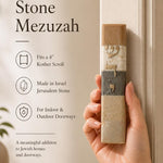 Woman's hand holding the Jerusalem Stone Mezuzah at natural scale, highlighting its texture, Hebrew lettering, and warm stone tones in a refined setting.