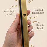Person holding a gold and black aluminum outdoor mezuzah showing its material and design features.