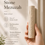 Person holding a Jerusalem stone mezuzah featuring Hebrew inscription, emphasizing the product's texture and design for a store presentation.