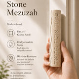 Person holding a Jerusalem stone mezuzah featuring Hebrew inscription, emphasizing the product's texture and design for a store presentation.