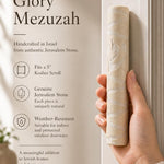 Person holding an authentic Jerusalem stone mezuzah, showing its natural texture and shape, in a warm, natural lighting setting highlighting the product's craftsmanship.