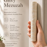 Person holding an authentic Jerusalem stone mezuzah, showing its natural texture and shape, in a warm, natural lighting setting highlighting the product's craftsmanship.