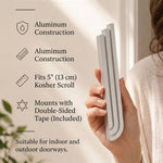 Person holding the exact silver mezuzah with natural lighting and generous negative space around.