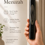 Person naturally holding the black marble mezuzah showing its size, texture, and craftsmanship for a premium product display.
