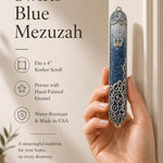 Female hand presenting the Elegant Swirls Blue Mezuzah in a premium store display setting.