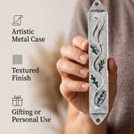 Person holding a botanical style leaves mezuzah case made from pewter and hand painted green enamel.