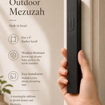 Person holding a precise, scaled black aluminum mezuzah, showcasing its design, material, and mounting details for a premium product feature.