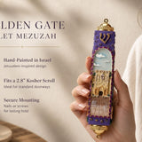 Person holding the Golden Gate Violet Mezuzah, showcasing its Jerusalem-inspired design and violet and gold tones, in a natural setting.