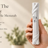 Hand-held white acrylic mezuzah case featuring curved edges and detailed Jerusalem masonry relief.