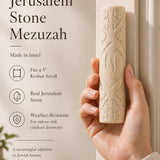 Person holding the authentic Jerusalem stone mezuzah, showcasing its carved leaf motif and natural cream color.