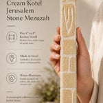 Hand holding the Old City cream Jerusalem stone mezuzah in natural light showing grain and texture.