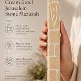 Hand holding the Old City cream Jerusalem stone mezuzah in natural light showing grain and texture.