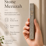 Person naturally holding the handcrafted gray Jerusalem stone mezuzah, showcasing its texture and size in a premium style.