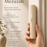 Person holding the authentic Jerusalem stone Golden Arch Mezuzah showing its texture and craftsmanship for a premium store display.