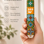 Hand holding the Toscana ceramic mezuzah case featuring intricate geometric patterns and a central Hebrew letter Shin.