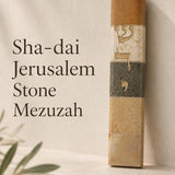 Handcrafted Jerusalem stone mezuzah case featuring gold Hebrew Sha-dai lettering, set against a pale limestone background.