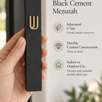 Close-up of the dimensional raised gold Shin on the smooth matte black cement face of the Timeless Israeli mezuzah case