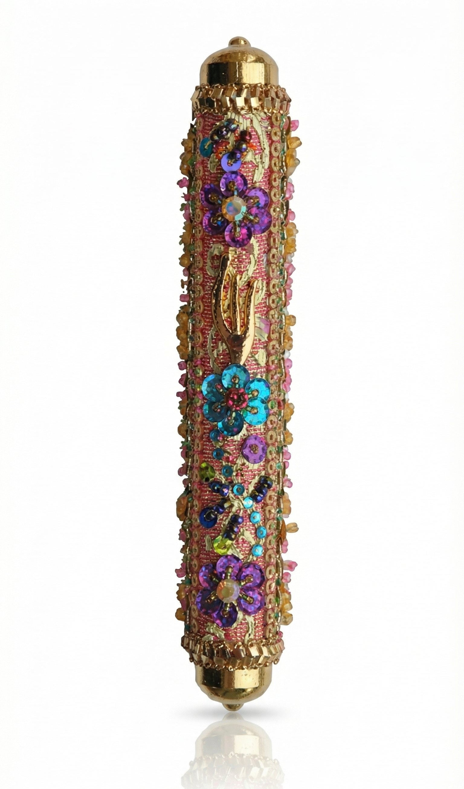 Intricate handmade Mezuzah decorated with colorful sequins and stones, mounted on a clean white background with soft reflection.