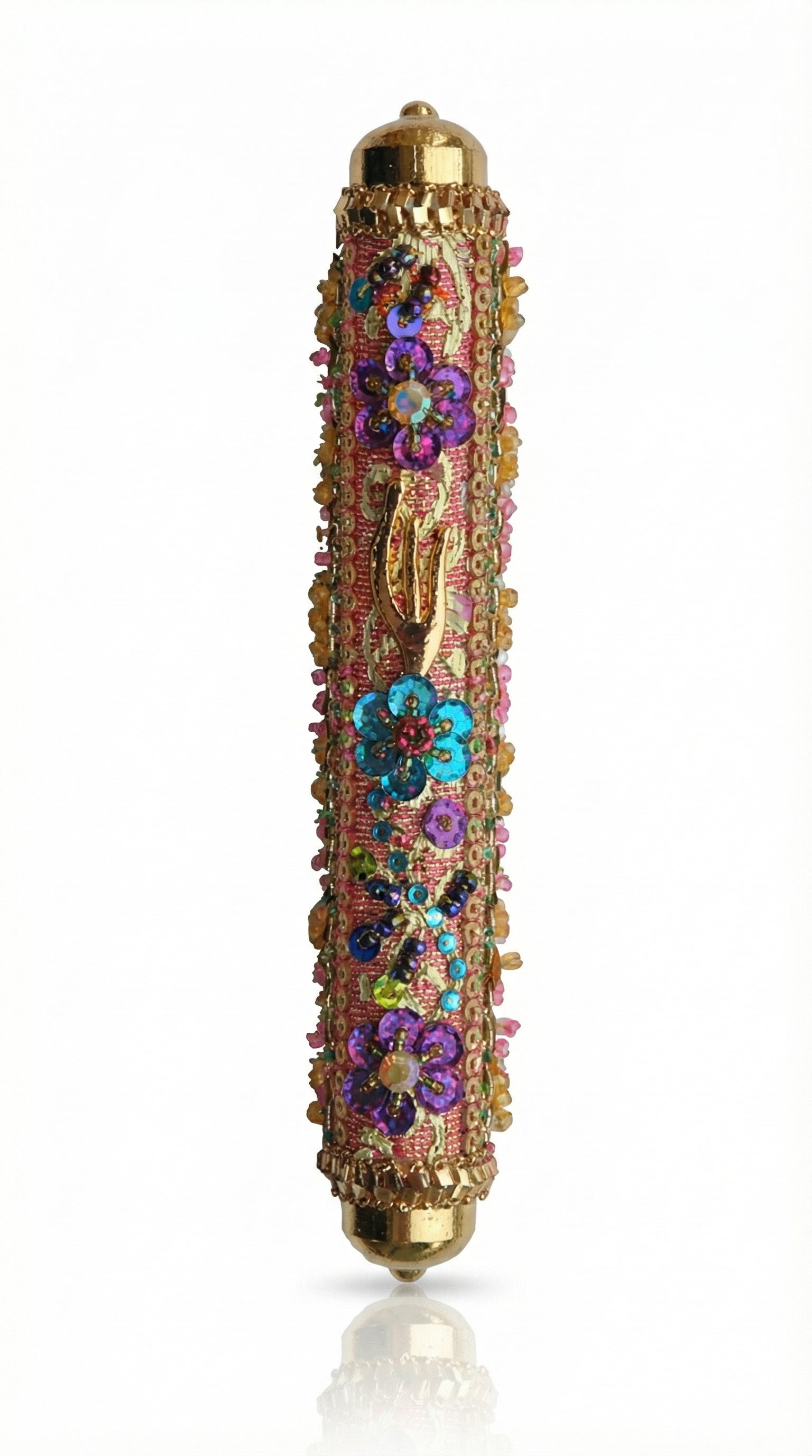 Intricate handmade Mezuzah decorated with colorful sequins and stones, mounted on a clean white background with soft reflection.