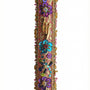Intricate handmade Mezuzah decorated with colorful sequins and stones, mounted on a clean white background with soft reflection.