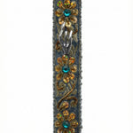 Handmade silver mezuzah decorated with colorful sequins and stones, crafted with intricate details and finished with a polished look, mounted on a white background.