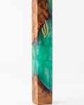Artistic Olive Wood Emerald Green Resin Mezuzah standing on a white studio background, a handmade Israeli mezuzah case pairing warm olive wood grain with translucent emerald green resin and a gold Shin, made for a 6-inch kosher scroll