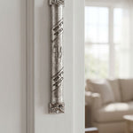 Heritage hammered pewter mezuzah on inside doorway reveal, depicting textured silver finish, Hebrew scroll accents, and rounded profile for traditional Jewish home decor.