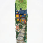 Detailed mezuzah with engraved Hebrew letters and decorative motifs on a white studio background with soft reflection.