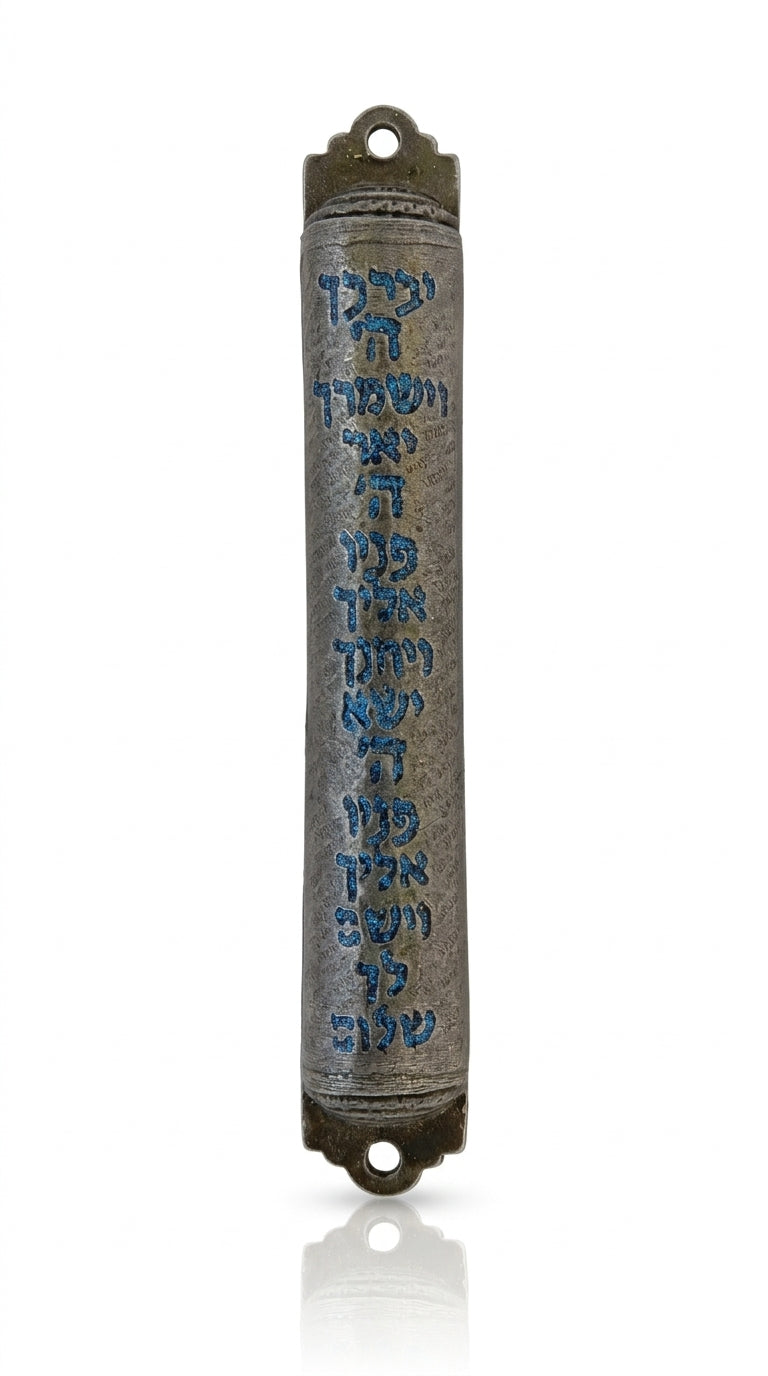 Blue pewter mezuzah with intricate Hebrew script and decorative motifs, displayed on a polished white studio surface with soft reflection.