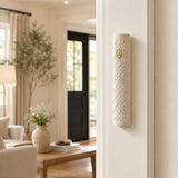 Indoor scene with Jerusalem stone mezuzah mounted on a residential doorpost during daytime, showcasing its carved lattice pattern and gold-tone shin.