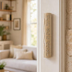 Real Jerusalem stone mezuzah mounted on a doorpost in an indoor setting, showcasing its natural cream color and Hebrew blessing inscription.