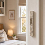 Real Jerusalem stone mezuzah mounted vertically on a residential doorpost at entrance, positioned within upper third for authentic setting.