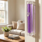 Indoor doorway scene showing purple lucite mezuzah mounted on the door frame for home blessing.