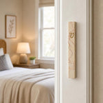 Real Jerusalem stone mezuzah mounted vertically on a residential doorpost, showcasing rose-veined cream natural stone with gold-tone Hebrew letter.