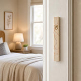 Real Jerusalem stone mezuzah mounted vertically on a residential doorpost, showcasing rose-veined cream natural stone with gold-tone Hebrew letter.