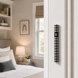 Realistic indoor scene showing grooved black aluminum mezuzah mounted vertically on a residential doorpost on the right side of the doorway.