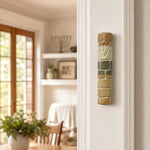Real Jerusalem stone Mezuzah mounted vertically on a residential doorpost in a natural indoor setting.