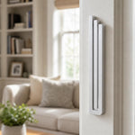 Realistic indoor scene showing the modern silver pyramid mezuzah mounted on a residential doorpost at entryway.